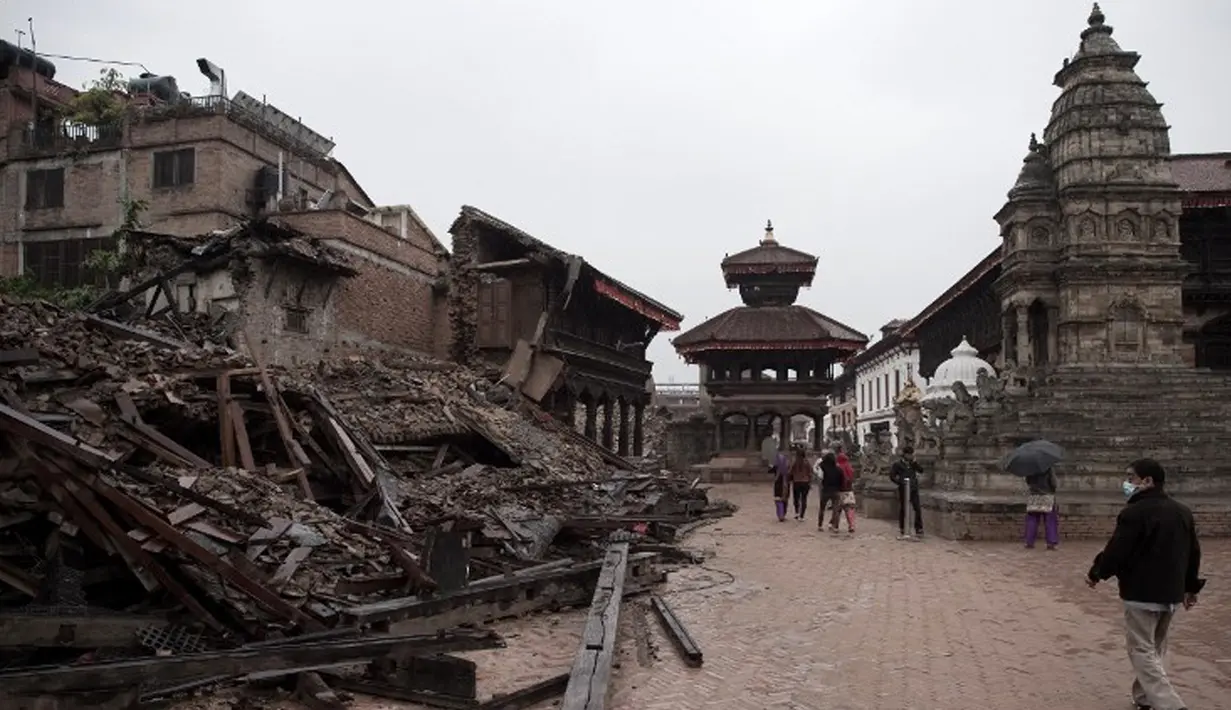 Pejalan kaki melintas di sisi salah satu bangunan bersejarah yang hancur akibat gempa berkekuatan 7,8  di sekitar Kathmandu, Nepal  (30/4/2015). Gempa berkekuatan 7,8 yang meluluhlantakkan Nepal pada 25 April 2015 lalu. (Nicolas Asfouri/AFP)
