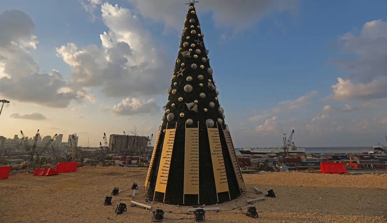Sebuah pohon Natal dengan daftar nama korban yang tewas dalam insiden ledakan di Pelabuhan Beirut terlihat di dekat silo gandum yang rusak di Beirut, Lebanon (22/12/2020). (Xinhua/Bilal Jawich)