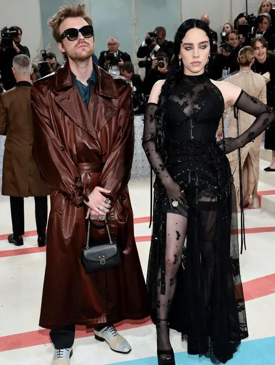 Billie Eilish terlihat stunning dengan gaun menerawang hitam. Ia ber-partner dengan sang kakak Finneas yang mengenakan trench coat coklat metalik di Met Gala 2023. [Foto: @themetgalaofficial]