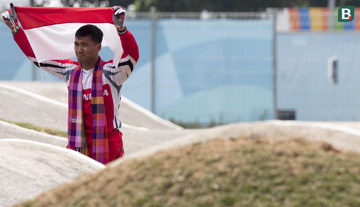 Pebalap sepeda BMX Indonesia, I Gusti Bagus Saputra, mengibarkan bendera usai berlaga pada Asian Games di Pulomas BMX Center, Jakarta, Sabtu (25/8/2018). Bagus Saputra meraih medali perak dengan catatan waktu 34,314 detik. (Bola.com/Peksi Cahyo)