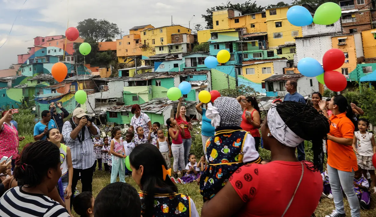 Warga merayakan peresmian proyek seni seniman Prancis, Tarik Bouanani di kawasan kumuh El Pesebre, pinggiran Medellin, Kolombia, 19 Juni 2017. Tarik melukis 230 rumah sebagai bagian dari proyek seninya membentuk mural raksasa. (JOAQUIN SARMIENTO/AFP)