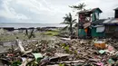 Warga berjalan melewati sebuah rumah yang rusak akibat terjangan topan Phanfone di Tacloban, Provinsi Leyte, Filipina, Rabu (25/12/2019). Topan membuat jutaan warga di negara yang mayoritas beragama Katolik itu merayakan Natal dengan kesedihan. (Bobbie ALOTA/AFP)