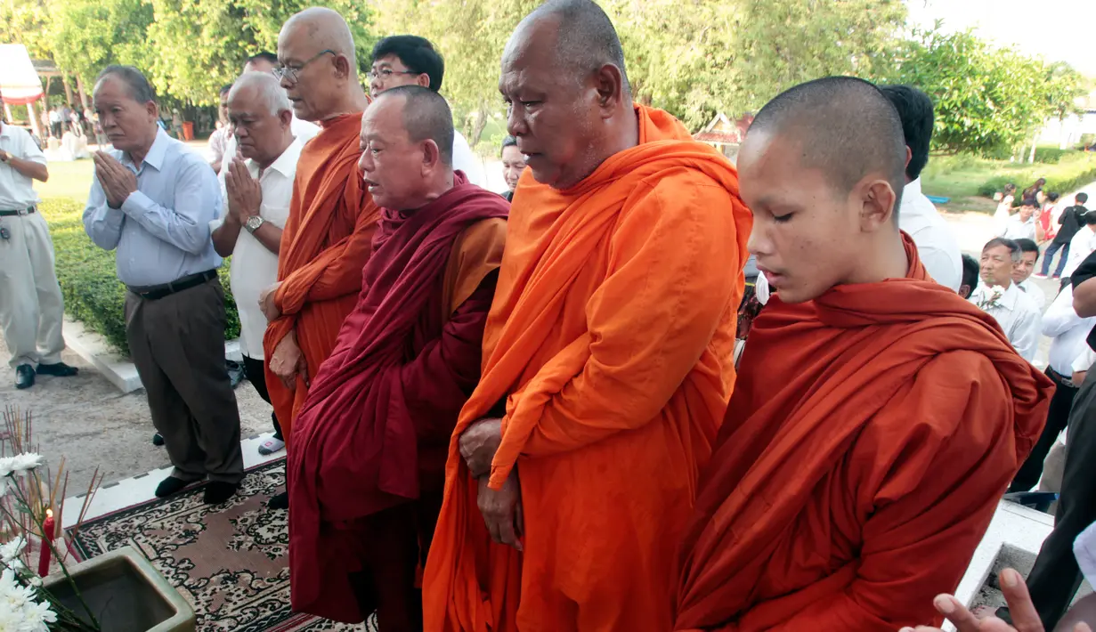 Sejumlah biksu bersama warga berdoa di depan sebuah stupa yang berisi ratusan tengkorak manusia dan tulang korban rezim Khmer Merah di Choeung Ek memorial, Kamboja (17/4). (AP Photo/Heng Sinith)