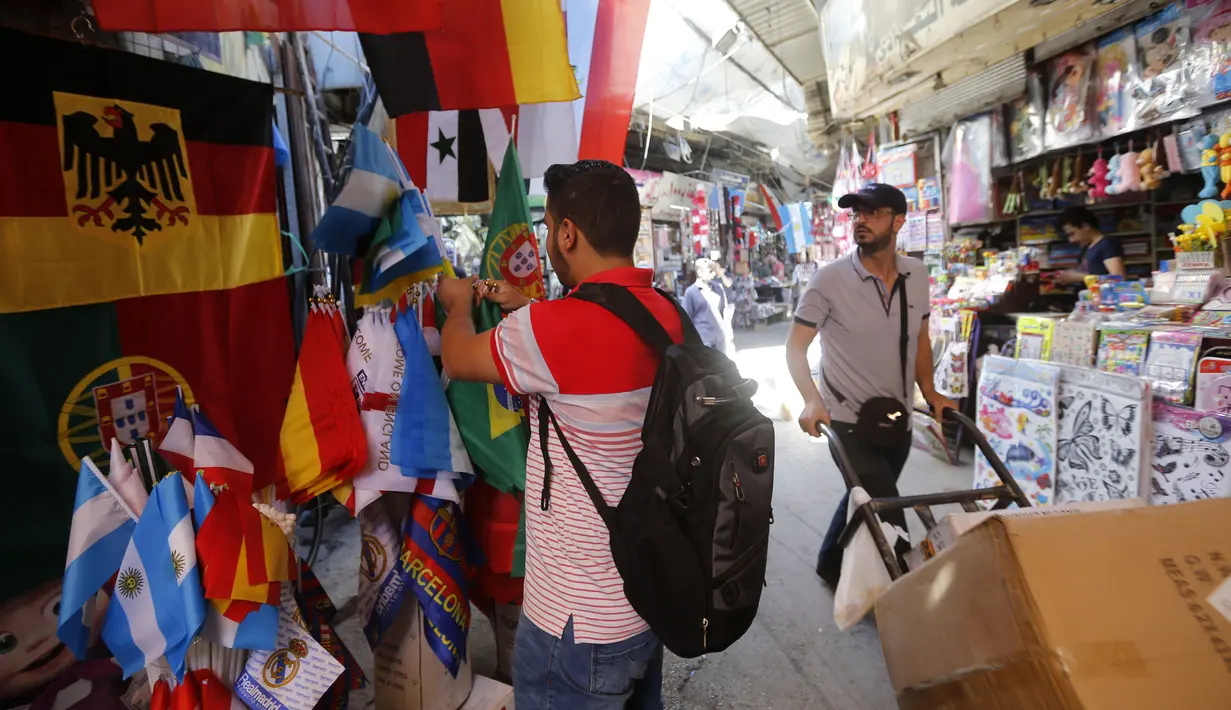 Pembeli mencari pernak-pernik negara-negara yang berpartisipasi pada Piala Dunia FIFA 2018 di jalan pasar di kota tua Damasku, Suriah (6/6). Piala Dunia akan digelar pada 14 Juni 2018 di Rusia. (AFP Photo/Louai Beshara)