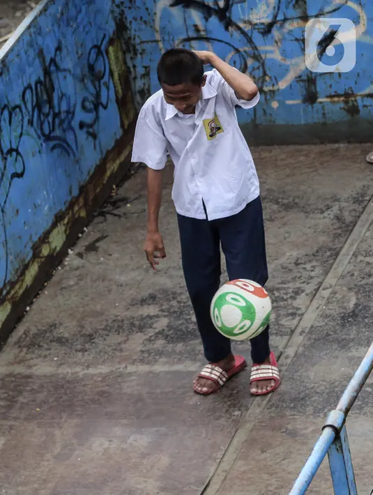 Seorang anak bermain sepak bola dalam bak truk di kawasan Cengkareng, Jakarta, Rabu (23/2/2022). Minimnya lahan bermain di kawasan tersebut membuat anak-anak memanfaatkan tempat yang bukan semestinya untuk bermain bola. (Liputan6.com/Johan Tallo)