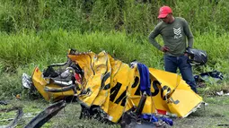 Warga melihat sisa puing bus sekolah usai mengalami kecelakaan di Yaguachi-Milagro, Ekuador, Jumat (14/1). Dilaporkan sedikitnya 20 orang tewas dan 17 lainnya mengalami luka-luka. (AFP PHOTO/MAURICIO DE LA CADENA)