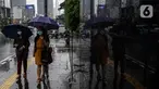 Pejalan kaki menggunakan payung saat hujan di kawasan Jakarta, Selasa (16/2/2021). Setelah memulai vaksinasi COVID-19 tahap pertama dengan sasaran petugas kesehatan, kini pemerintah menargetkan lansia dan petugas pelayanan publik untuk penerima vaksinasi tahap kedua. (Liputan6.com/Johan Tallo)