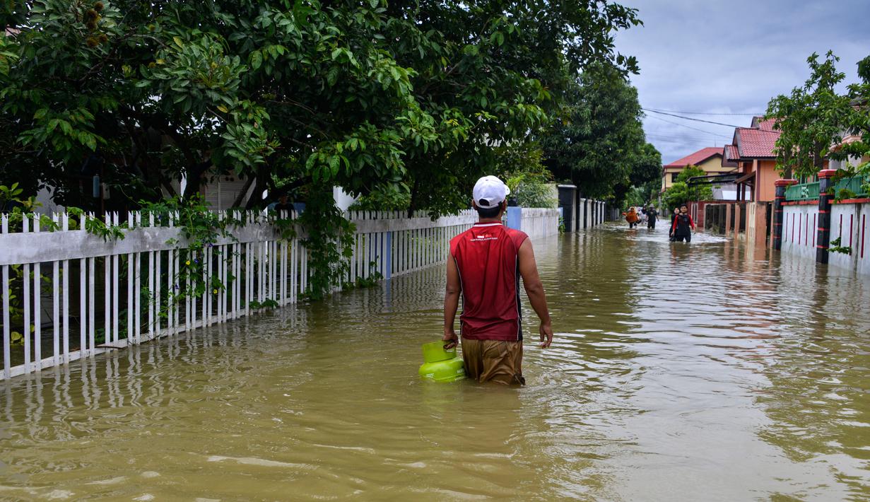 Seorang pria menerebos banjir setelah tiga hari diguyur hujan lebat di Banda Aceh, Aceh, Sabtu (9/5/2020). Banjir akibat intensitas hujan tinggi tersebut mengakibatkan sebagian besar kawasan di ibu kota Provinsi Aceh ini digenangi air. (Photo by CHAIDEER MAHYUDDIN/AFP)