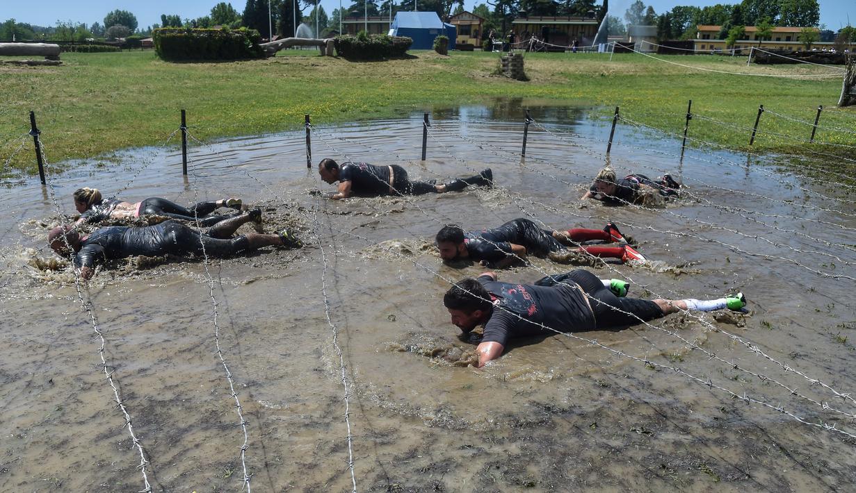 Peserta lomba melewati kawat berduri saat mengikuti "Legion Run" di Roma, Italia, Sabtu (13/4). Peserta harus melewati rintangan seperti dari lumpur, es dan kawat berduri dengan jarak tempuh 5 kilometer. (AFP PHOTO / Andreas SOLARO)
