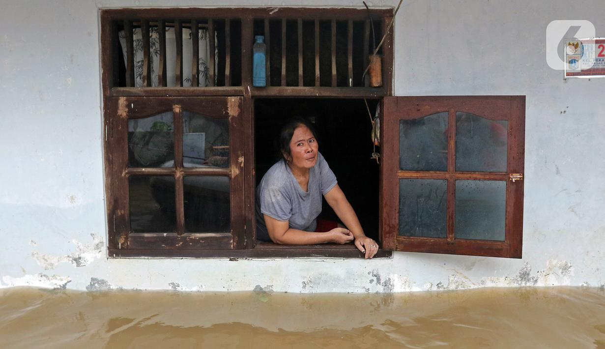Warga melihat keluar jendela saat banjir di RW 07, Kelurahan Pekayon, Jakarta Timur, Sabtu (20/2/2021). Banjir di kawasan tersebut terjadi akibat curah hujan yang tinggi. (Liputan6.com/Herman Zakharia)