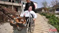 Li Juhong didorong menggunakan kursi roda di Chongqing, Cina. Selama 15 tahun terakhir ia berhasil membantu masyarakat desa yang sakit dengan berprofesi sebagai dokter, untuk menyiasatinya, ia menggunakan bangku kayu sebagai "kaki" nya. (Chinanews.com)