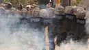 Polisi antihuru-hara berlindung dari serangan gas air mata mahasiswa Venezuela Central University, Caracas, Venezuela (21/11). Mereka Menuntut peningkatan anggaran beasiswa dan membuka kembali kafetaria universitas. (AP Photo/Ariana Cubillos)