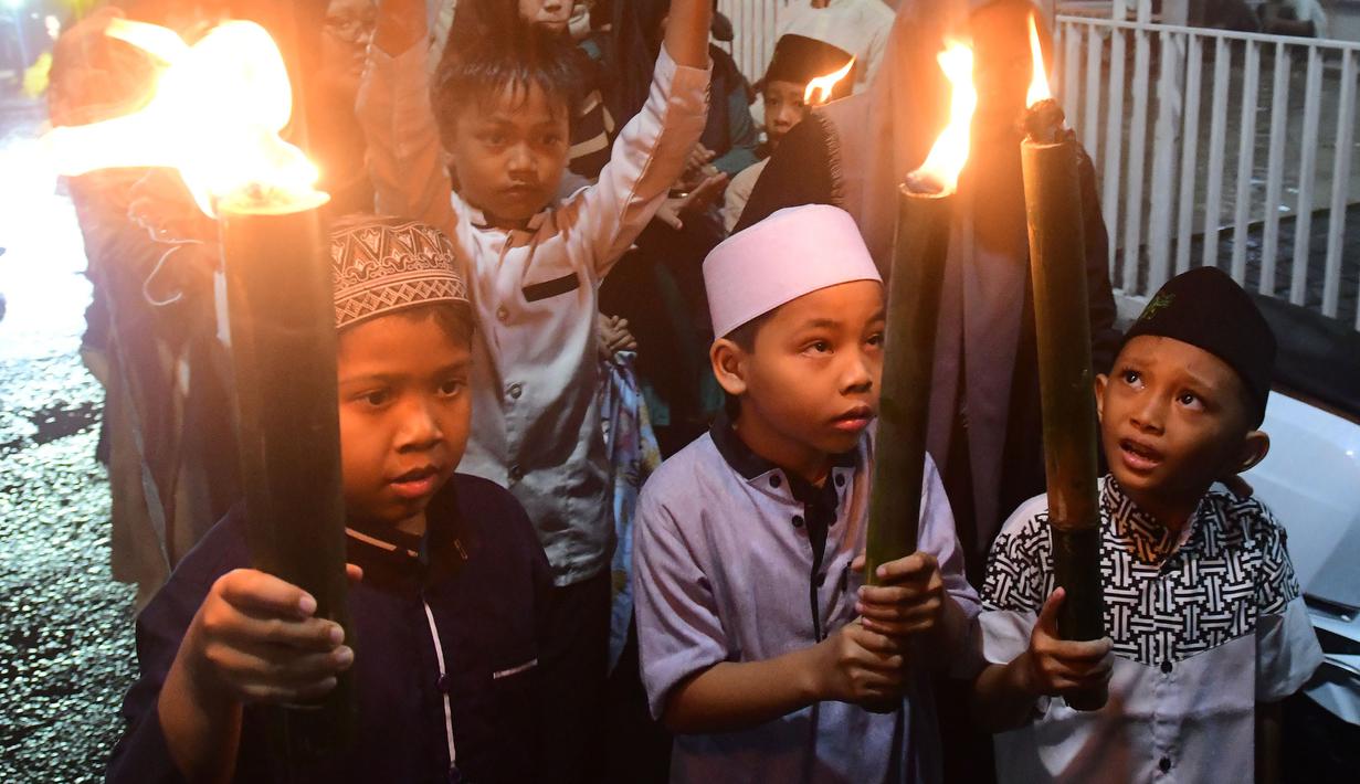 Cahaya obor bambu yang dibawa peserta menerangi jalanan lingkungan permukiman, menghadirkan suasana hangat dan penuh kebersamaan di tengah masyarakat. Tampak dalam foto, anak-anak saat mengikuti pawai obor di kawasan Cinere,  Depok, Senin (16/2/2026). (merdeka.com/Arie Basuki)