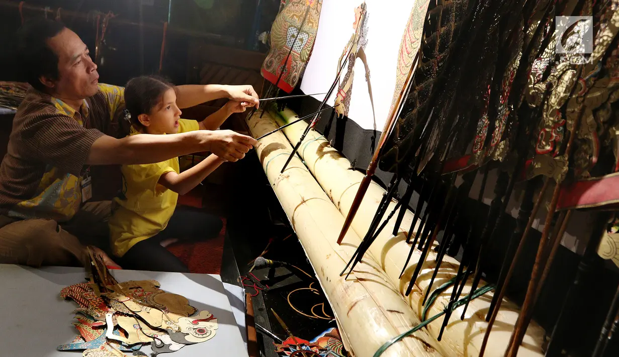 Dalang Ki Purbo Asmoro mengajar siswa belajar mendalang pada pagelaran wayang kulit di Jakarta Intercultural School (JIS) Elementary, Jakarta, Kamis (2/11). Pagelaran ini merupakan bagian dari JIS cultural week. (Liputan6.com/Fery Pradolo)
