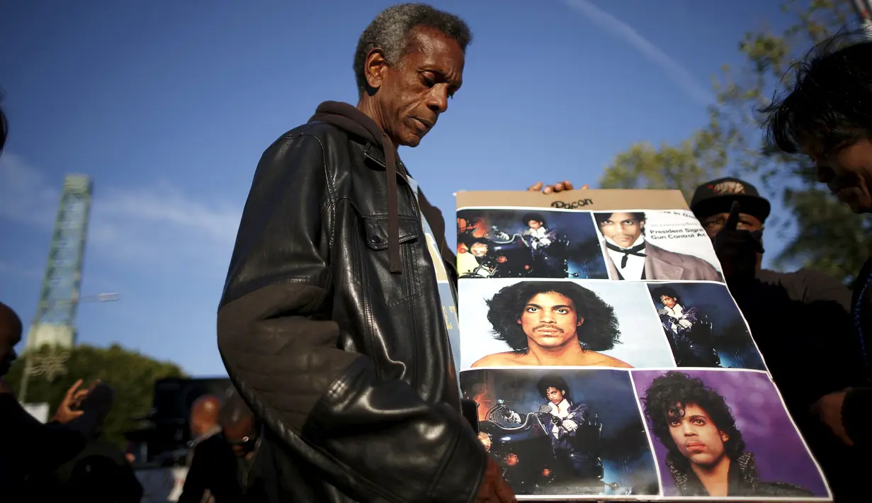Penggemar membawa poster untuk mengenang penyanyi legendaris dunia, Prince, di Los Angeles, California, Kamis (21/4). Prince ditemukan dalam posisi telentang dan keadaannya sudah tak bernafas di Paisley Park, Minnesota. (REUTERS/Lucy Nicholson)