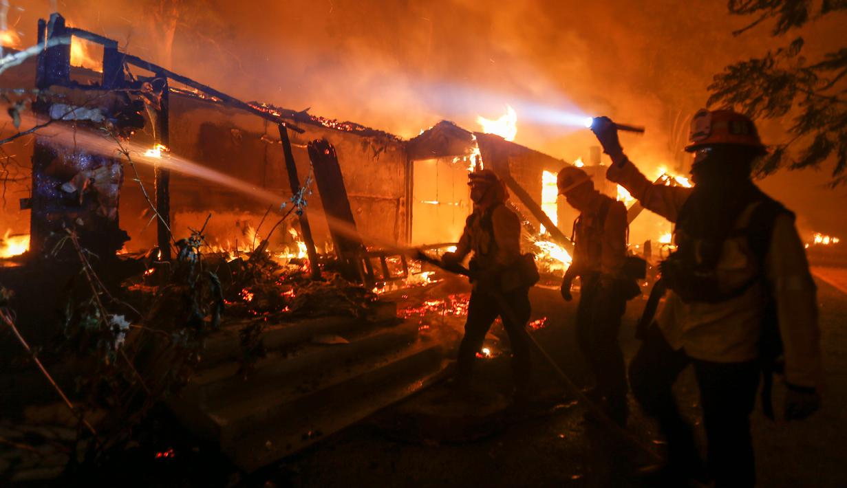 Petugas pemadam kebakaran berjuang memadamkan kobaran api di sebuah rumah di Malibu, California, AS, Jumat (9/11). Api Woolsey pertama kali dilaporkan terdeteksi dekat Thousand Oaks. (AP Photo/Ringo H.W. Chiu)