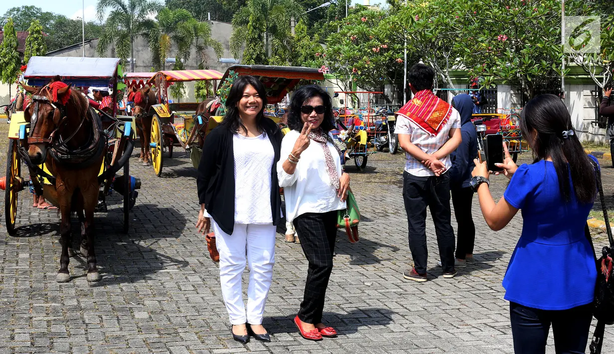 Warga berfoto diantara andong dan betor yang akan digunakan dalam arak-arakan ngunduh mantu Kahiyang-Bobby di Medan, Rabu (22/11). (Liputan6.com/Johan Tallo)
