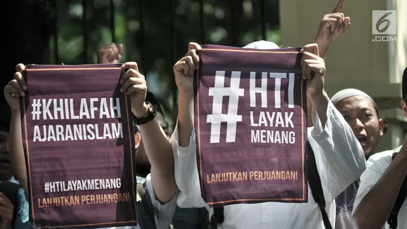 Massa dari HTI membentangkan poster saat menunggu putusan sidang gugatan di luar Gedung Pengadilan Tata Usaha Negara (PTUN), Jakarta, Senin (7/5).