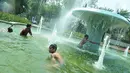 Sejumlah anak mandi di bundaran air mancur Jalan Teuku Umar, Jakarta Pusat, Sabtu (23/9). Cuaca panas ibu kota memaksa anak-anak menceburkan diri di kolam untuk menyejukkan badan. (Liputan6.com/Helmi Afandi)
