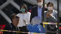 Seorang pekerja yang mengenakan alat pelindung diri menyeka tenggorokan seorang pria saat tes COVID-19 di tempat pengujian setelah pihak berwenang memerintahkan putaran ketiga dari tiga tes COVID-19 berturut-turut untuk penduduk di Distrik Chaoyang, Beijing, China, Sabtu (7/5/2022). (AP Photo/Mark Schiefelbein)