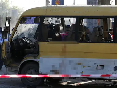 Petugas keamanan dan pemadam kebakaran saat mengecek kondisi minibus yang terkena serangan bunuh diri di Kabul, Afghanistan, Senin (20/6). Sebanyak 14 orang tewas akibat serangan ini. (REUTERS / Omar Sobhani)