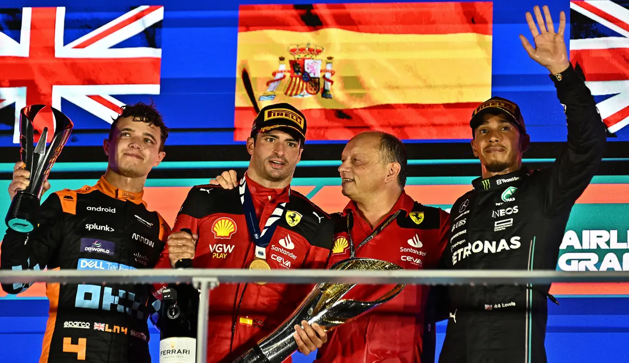 (Dari kiri) peringkat kedua, Lando Norris (McLaren), juara, Carlos Sainz (Ferrari) didampingi Team Principal, Frederic Vasseur dan peringkat ketiga, Lewis Hamilton (Mercedes) saat merayakan kemenangan di podium usai balapan F1 GP Singapura 2023 di Marina Bay Street Circuit, Singapura, Minggu (17/9/2023) malam WIB. (AFP/Lillian Suwanrumpha)