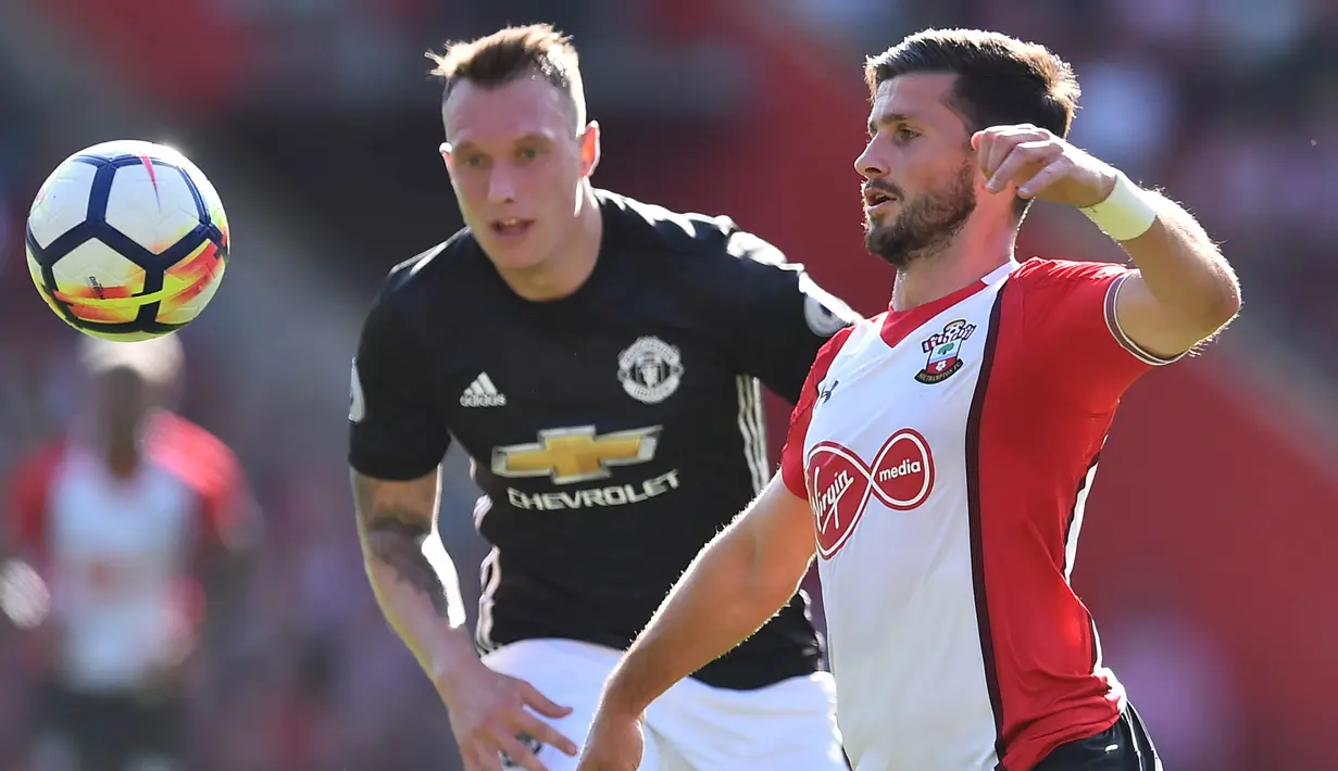 Bek Manchester United, Phil Jones, berebut bola dengan striker Southampton, Shane Long, pada laga Premier League di Stadion St Mary's, Sabtu (23/9/2017). Manchester United menang 1-0 atas Southampton. (AFP/Glyn Kirk)