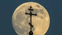 Bulan purnama di balik salib di atas sebuah gereja ortodoks di kota Rossosh di Voronezh, Rusia, pada Selasa 25 Mei 2021 (Kirill Kudryavtsev / AFP / Getty)