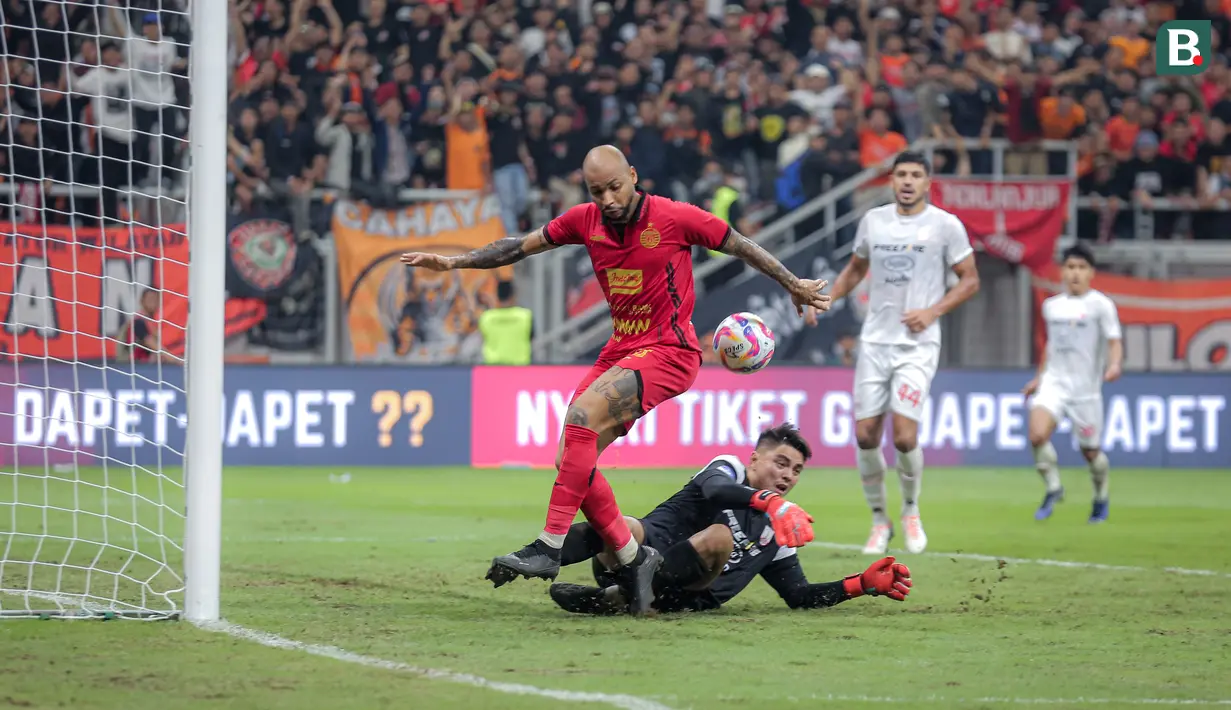Kiper Persis Solo, Gianluca Claudio (tengah) berhasil menghalau bola tendangan pemain Persija Jakarta, Gustavo Almeida pada laga lanjutan BRI Liga 1 2024/2025 di Jakarta International Stadium (JIS), Jakarta Utara, Sabtu (24/08/2024). (Bola.com/Bagaskara Lazuardi)