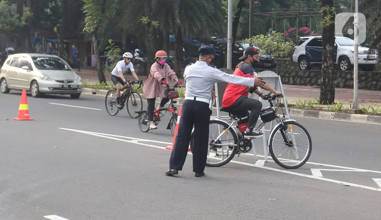 Petugas mengarahakan pesepeda non road bike saat memasuki JLNT Kampung Melayu-Tanah Abang, Jakarta, Minggu (30/5/2021). Uji coba kedua ini bertujuan kembali mendapatkan masukan dari penggiat sepeda secara lengkap baik dari sisi operasional maupun teknis kedepannya. (Liputan6.com/Herman Zakharia)