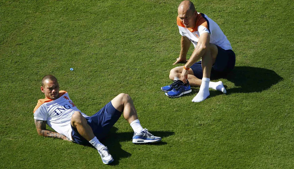 Dua pemain inti Timnas Belanda, Wesley Sneijder (kiri) dan Arjen Robben memilih duduk-duduk santai di lapangan usai menjalani sesi latihan di Rio de Janeiro, (24/6/2014). (REUTERS/Ricardo Moraes)