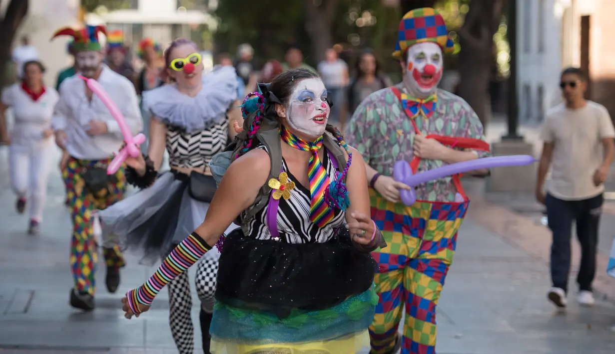 Para peserta berdandan seperti badut berlarian selama acara parodi tahunan "Running of the Clowns" di Pasadena, California pada 20 Oktober 2019. Lari dikejar kawanan badut ini merupakan parodi yang mengolok-olok lomba dikejar banteng di Spanyol. (Mark RALSTON / AFP)