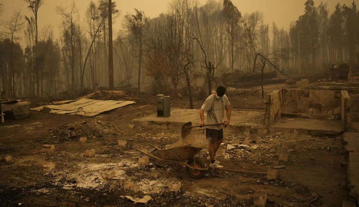 Yeremy Escanilla bekerja membersihkan puing-puing sisa-sisa rumahnya yang hancur akibat kebakaran hutan di Santa Juana, Chile, Minggu (5/2/2023). Gelombang panas musim panas yang terik mempersulit upaya untuk mengendalikan kebakaran. (AP Photo/Matias Delacroix)