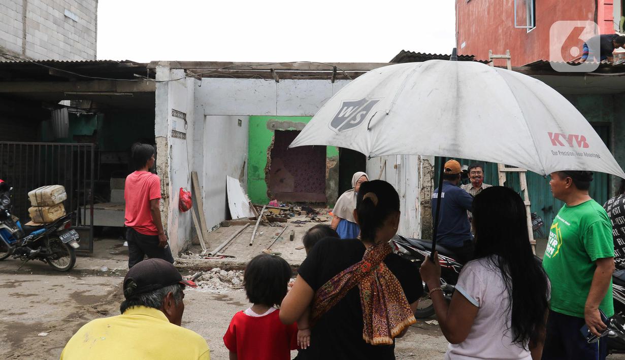 Warga melihat rumah yang dibongkar saat pembebasan lahan proyek Jalan Tol CIbitung-CIlincing seksi 4 di kawasan Semper Timur, Cilincing, Jakarta Utara, Selasa (8/11/2022). PT Cibitung Tanjung Priok Port Tollways (CTP Tollways) sebagai Badan Usaha Jalan Tol (BUJT) mencatat progres pembebasan lahan untuk seksi 4 sepanjang 7,28 km telah mencapai 100% dan ditargetkan pembangunannya selesai pada akhir tahun 2022. (Liputan6.com/Herman Zakharia)