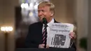 Presiden Donald Trump tersenyum saat menunjukkan surat kabar dengan tajuk utama bertuliskan "Trump dibebaskan" di Ruang Timur Gedung Putih, Washington (6/2/2020). Para senator AS memutuskan bahwa Trump tidak bersalah dalam sidang pemakzulan. (AP Photo/Evan Vucci)