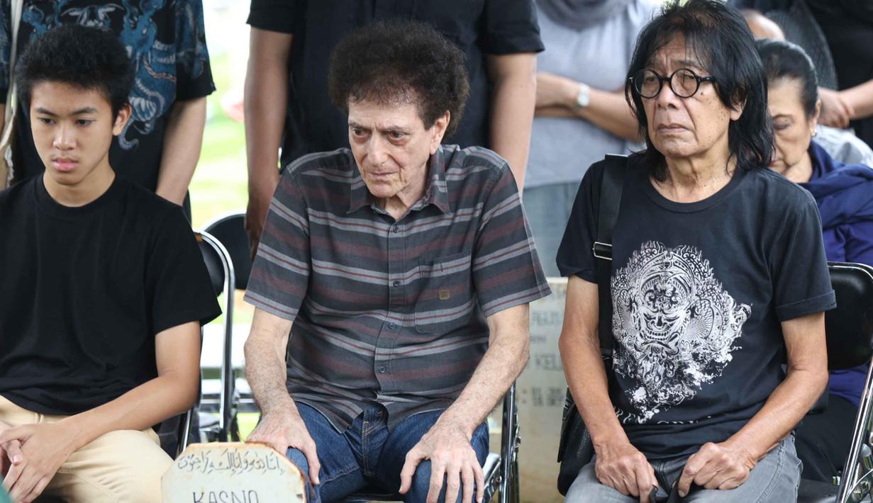 Selain bersama God Bless, ia juga terlibat dalam berbagai proyek musik penting seperti Gong 2000 dan berkontribusi besar dalam perkembangan musik rock tanah air. Tampak dalam foto, ekspresi vokalis grup band God Bless, Ahmad Albar (tengah) bersama Ian Antono (kanan) menyaksikan prosesi pemakaman jenazah Donny Fattah di Tempat Pemakaman Umum (TPU) Kampung Kandang, Jagakarsa, Jakarta Selatan, Sabtu (7/3/2026). (Kapanlagi.com/Budy Santoso)