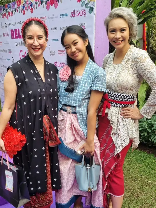 Novita Angie mengenakan tunik batik jumputan warna hitam yang dipadukan dengan rok batik dan bandana merah.  [@novitaangie]