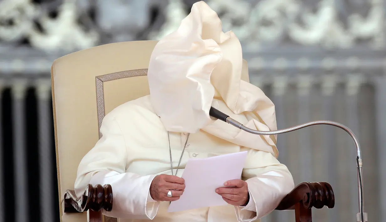 Embusan angin meniup jubah Paus Fransiskus yang sedang memberikan ceramah pada acara audiensi umum di Lapangan Santo Petrus, Vatikan, Rabu (16/5). Tiupan angin tersebut membuat wajah Paus tertutup jubah. (AP Photo/Alessandra Tarantino)