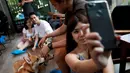 Seorang wanita berswafoto dengan anjing jenis Corgis di kafe anjing bernama Corgi In The Garden di Bangkok, Thailand. Untuk menghindari 12 hewan lucu tersebut dari rasa tertekan, pengelola juga memberlakukan sistem waktu bermain. (REUTERS/Soe Zeya Tun)