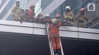Petugas pemadam kebakaran mengevakuasi korban kebakaran di Gedung Cyber 1, Jakarta, Kamis (2/12/2021). Kebakaran Gedung Cyber 1 mengakibatkan satu orang meninggal dunia. (Liputan6.com/Herman Zakharia)