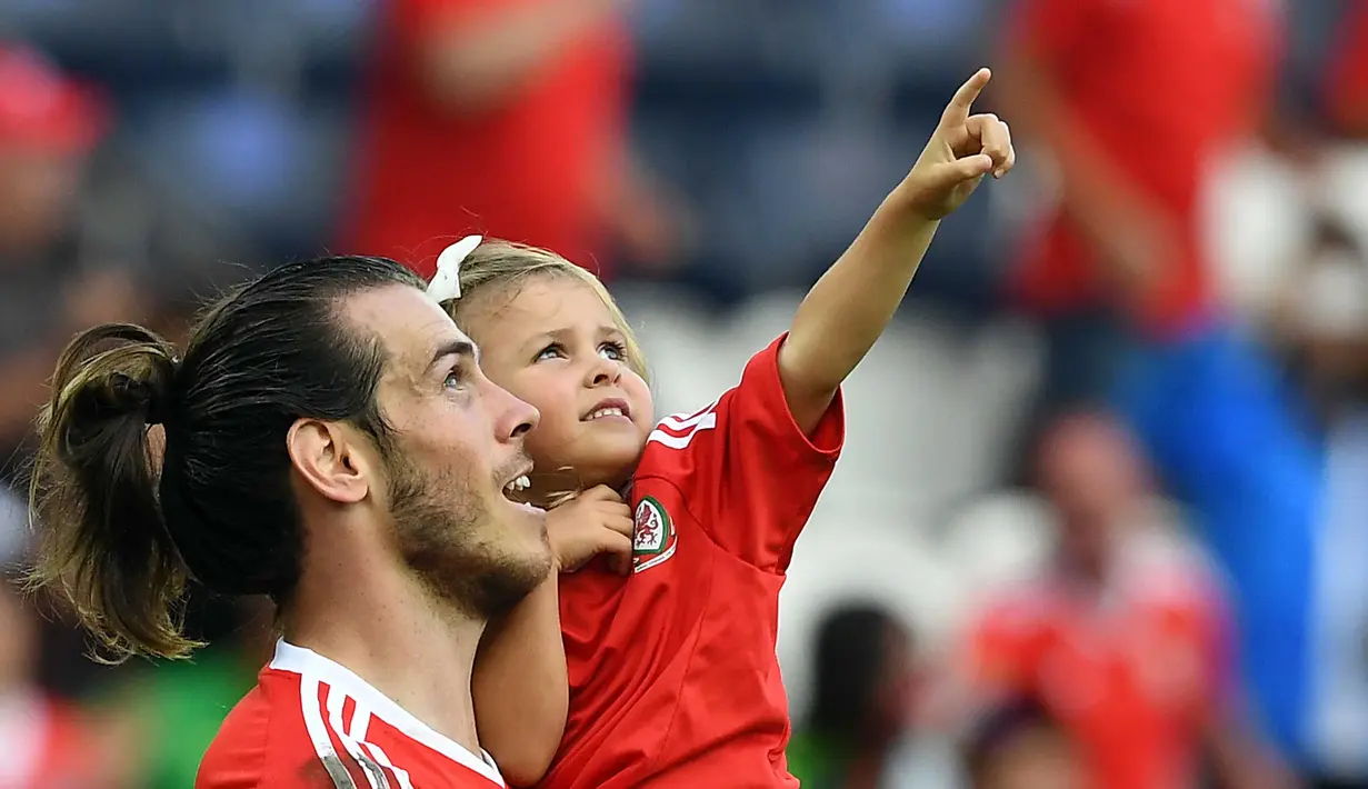 Pemain Wales, Gareth Bale menggendong putrinya usai laga melawan Irlandia Utara pada Piala Eropa 2016 di Parc des Princes, Paris, (25/6/2016). Wales Menang 1-0.  (EPA/Georgi Licovski)