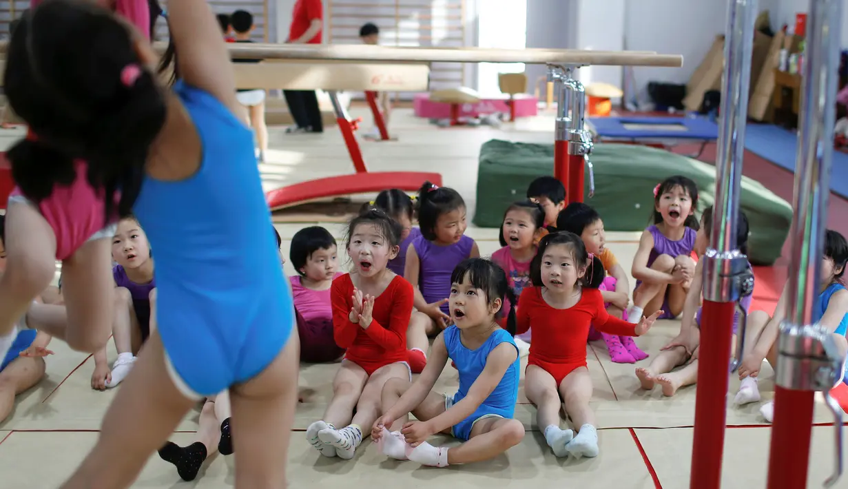 Murid-murid saling membantu saat mengikuti kelas senam lantai di sekolah atletik Shanghai Yangpu Youth Amateur, China (18/5). Sistem sekolah olahraga di China telah sangat membantu meraih kesuksesan dengan didikan kerasnya. (REUTERS/Aly Song)