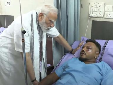 Sebuah tangkapan layar rekaman video yang diambil dan dirilis oleh Saluran Youtube Narendra Modi pada 13 Juni 2025 menunjukkan Perdana Menteri India Narendra Modi (kiri) bertemu dengan Vishwash Kumar Ramesh, satu-satunya yang selamat dari kecelakaan penerbangan Air India 171, di sebuah rumah sakit di Ahmedabad. (Narendra Modi Youtube Channel/AFP)