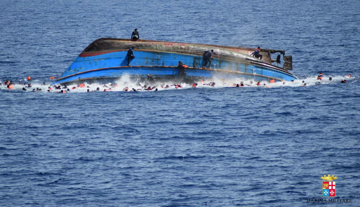 Foto yang dirilis Angkatan Laut (AL) Italia menunjukkan sebuah perahu yang berisi para migran terbalik di lepas pantai Libya, Rabu (25/5). Ratusan migran menceburkan diri ke laut, beberapa lainnya berusaha menyelamatakan diri (STR/AFP MARINA MILITARE/AFP)