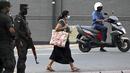 Seorang pejalan kaki melewati tentara yang berjaga di sepanjang jalan di Kolombo pada Sabtu (2/4/2022). Pasukan yang dipersenjatai dengan senapan serbu otomatis dikerahkan di Sri Lanka untuk mengendalikan massa, beberapa jam setelah presiden menyatakan keadaan darurat. (KODIKARA / AFP)