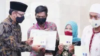 Buku nikah, kartu keluarga (KK), e-KTP dan Akta Kelahiran diserahkan secara simbolis oleh Wali Kota Bogor, Bima Arya kepada 43 pasangan yang baru saja melangsungkan pernikahan massal, Sabtu (11/12/2021). (Liputan6.com/Achmad Sudarno)