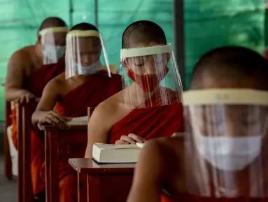 Para biksu muda mengenakan masker dan pelindung wajah saat belajar agama di Molilokayaram Educational Institute, Bangkok, Thailand, Rabu (15/4/2020). Sekitar 200 biksu muda tetap bersekolah kendati Thailand menutup semua sekolah selama lockdown akibat COVID-19. (AP Photo/Gemunu Amarasinghe)