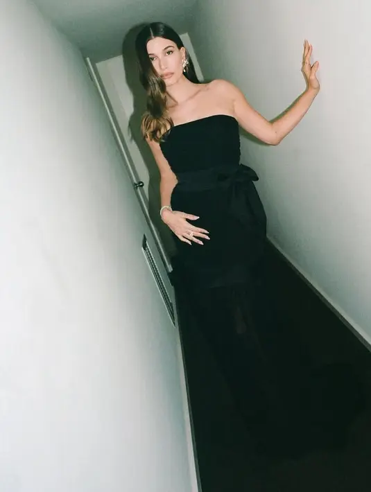 Gaun tersebut memiliki aksen strapless. Dengan bagian gaun panjang menyapu lantai model sheer serta aksen pita seperti di bagian pinggangnya.  [@haileybieber]