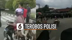 Seorang emak-emak menggunakan motor membawa banyak bebek dibantu oleh para mahasiswa untuk melewati barikade polisi.