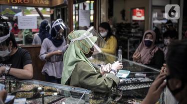 Pedagang mengenakan masker dan pelindung wajah saat melayani pembeli di  Pasar Kebayoran Lama, Jakarta Selatan, Senin (22/6/2020). Pasar Kebayoran Lama kembali buka setelah sebelumnya tutup selama tiga hari sejak 18 Juni 2020 akibat 14 pedagang positif COVID-19. (Liputan6.com/Faizal Fanani)